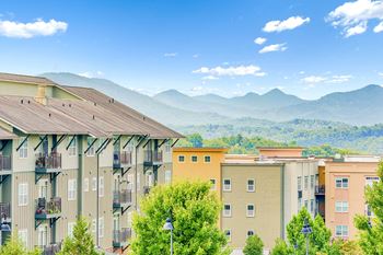 Apartment buildings with balconies overlooking a mountain range.